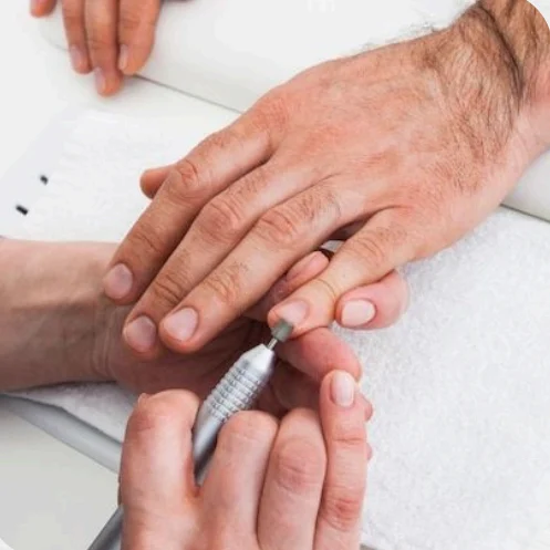 Close-up of a manicure being performed with a nail file on a hand.