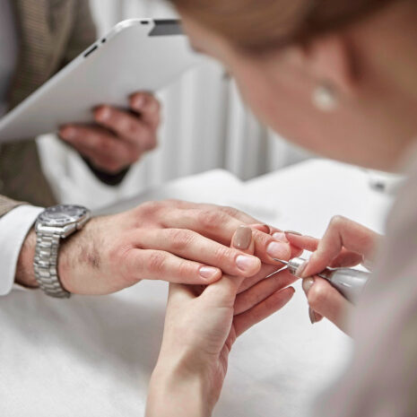 Close-up of a manicure being performed with a nail file on a hand.