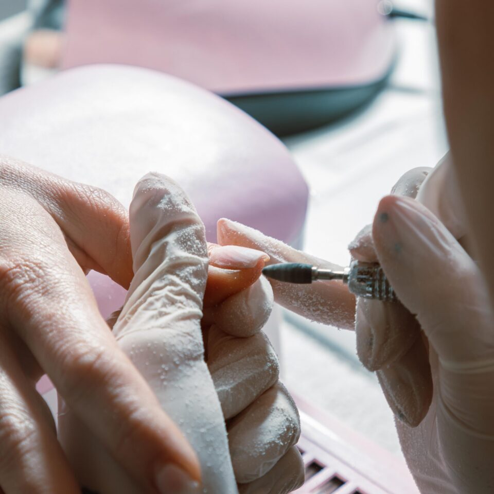 Close-up of a manicure being performed with a nail file on a hand.