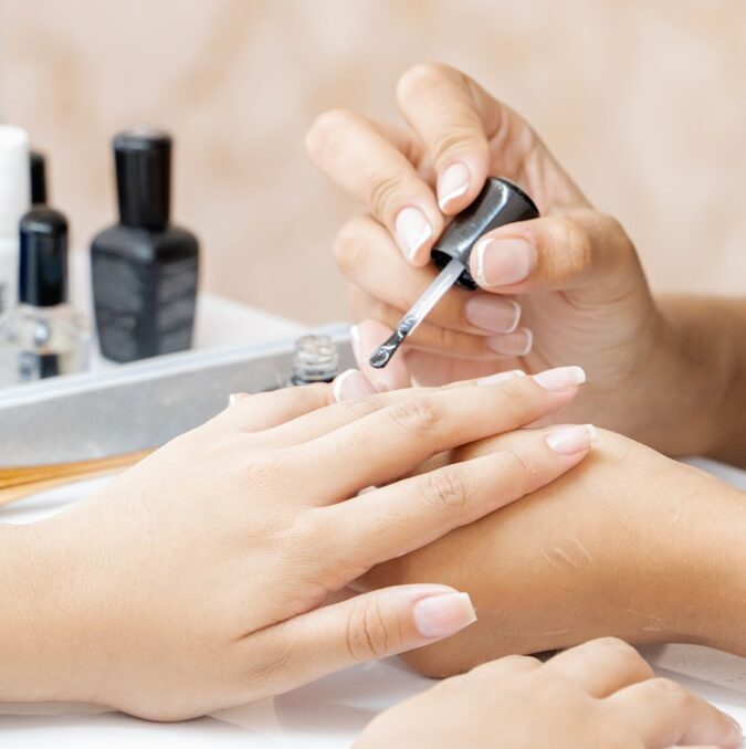Close-up of a manicure being performed with a nail file on a hand.